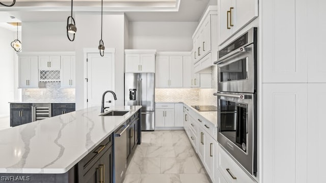 kitchen with an island with sink, pendant lighting, white cabinets, and stainless steel appliances