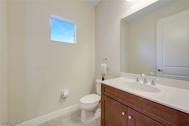 bathroom featuring tile patterned flooring, baseboards, vanity, and toilet