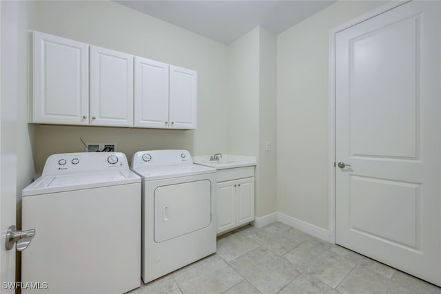 washroom featuring light tile patterned floors, separate washer and dryer, a sink, baseboards, and cabinet space