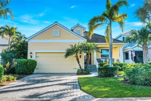 view of front of house with covered porch, decorative driveway, an attached garage, and a front yard