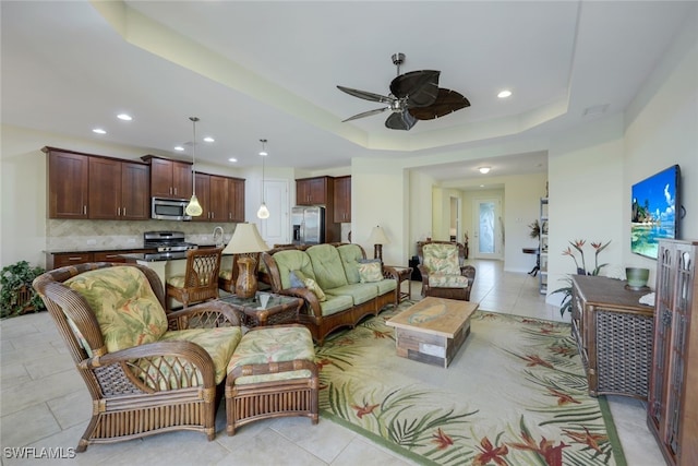 living room with ceiling fan, a tray ceiling, light tile patterned floors, and recessed lighting