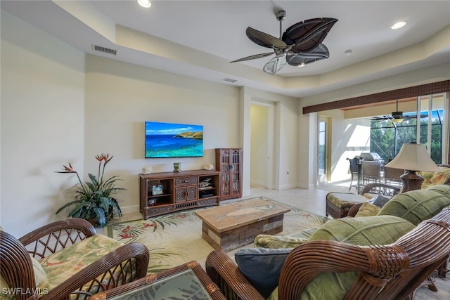 living area featuring ceiling fan, recessed lighting, visible vents, baseboards, and a raised ceiling