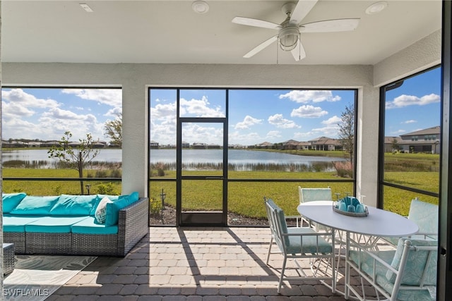 sunroom / solarium with ceiling fan and a water view