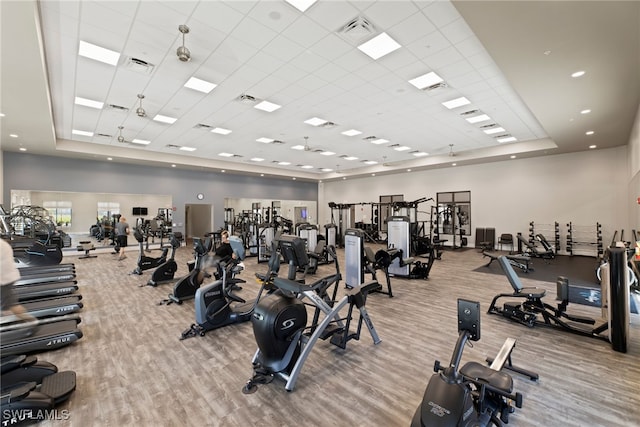 workout area featuring a tray ceiling and light hardwood / wood-style floors