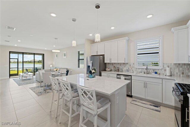 kitchen featuring appliances with stainless steel finishes, white cabinetry, hanging light fixtures, and sink