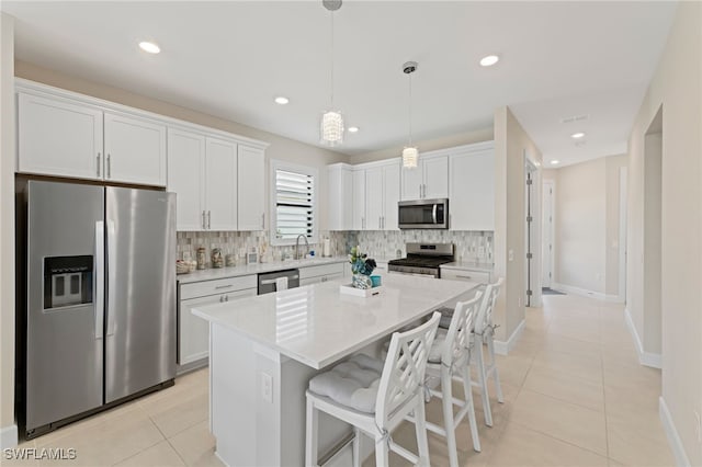 kitchen with appliances with stainless steel finishes, a center island, tasteful backsplash, white cabinets, and decorative light fixtures