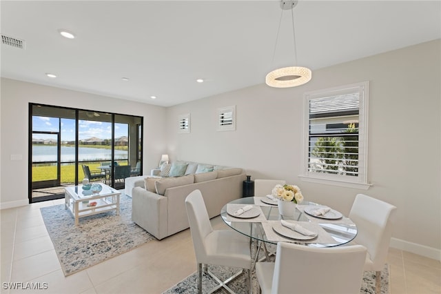 dining space featuring light tile patterned floors, a water view, and a healthy amount of sunlight