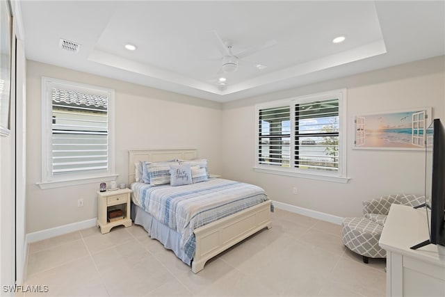 bedroom with ceiling fan, a tray ceiling, and multiple windows