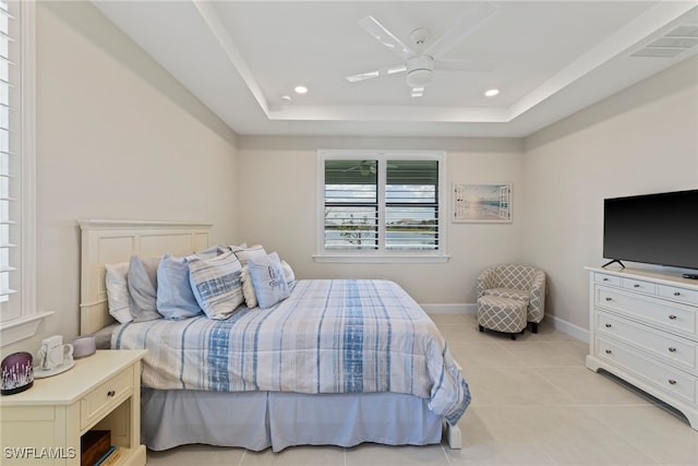 bedroom with light tile patterned flooring, ceiling fan, and a raised ceiling