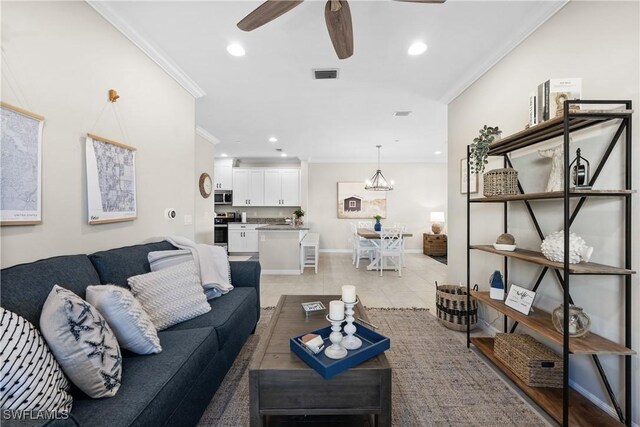 tiled living room featuring ceiling fan with notable chandelier and ornamental molding