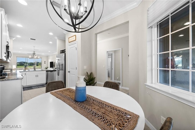 tiled dining room with sink, a chandelier, and ornamental molding