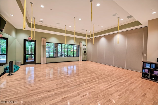 interior space featuring a raised ceiling, light hardwood / wood-style flooring, a wealth of natural light, and crown molding