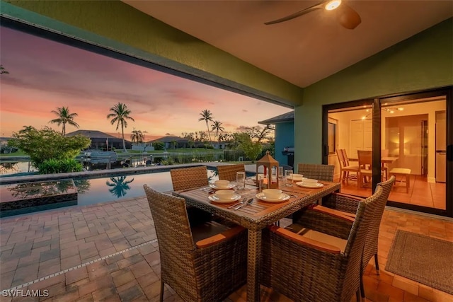 patio terrace at dusk featuring outdoor dining space and an outdoor pool
