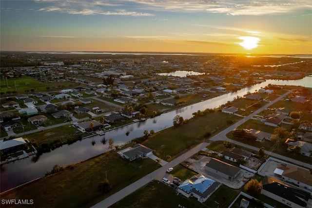 aerial view at dusk featuring a water view