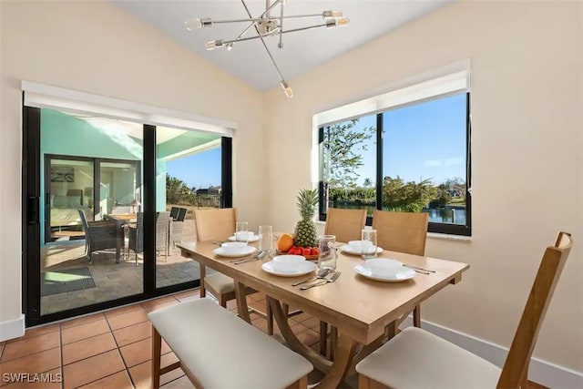 tiled dining space featuring a notable chandelier, plenty of natural light, and lofted ceiling