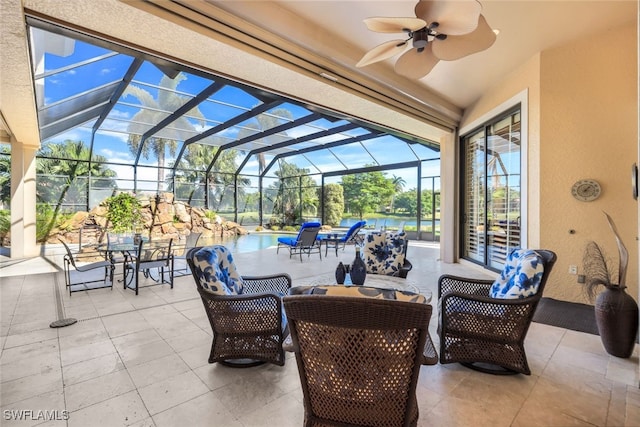 view of patio / terrace featuring an outdoor living space, a water view, glass enclosure, and ceiling fan