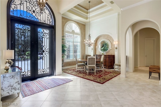 tiled entryway with french doors, a towering ceiling, an inviting chandelier, and ornamental molding