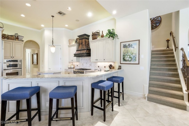 kitchen featuring premium range hood, hanging light fixtures, light stone counters, kitchen peninsula, and stainless steel appliances