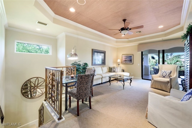 carpeted living room featuring a raised ceiling, ceiling fan, and ornamental molding