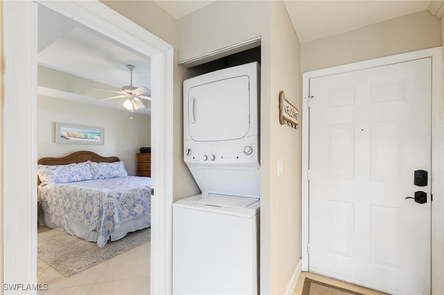 laundry area featuring ceiling fan, light tile patterned floors, and stacked washer and clothes dryer