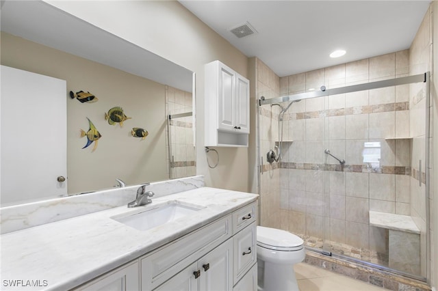 bathroom featuring tile patterned floors, vanity, toilet, and a shower with shower door