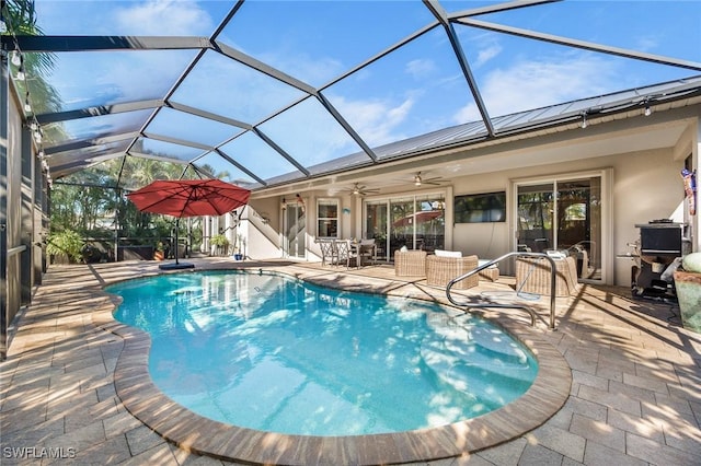 view of swimming pool with a patio area, ceiling fan, and glass enclosure