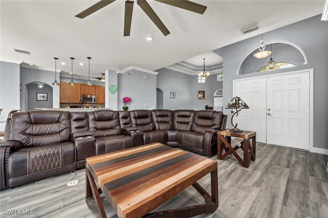 living room with hardwood / wood-style flooring, ceiling fan with notable chandelier, and crown molding