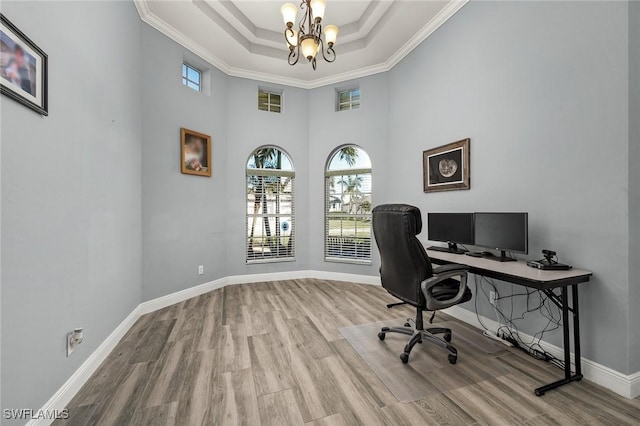 home office featuring a chandelier, ornamental molding, a tray ceiling, and light hardwood / wood-style flooring