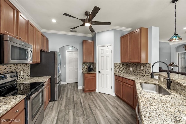 kitchen with backsplash, sink, hanging light fixtures, appliances with stainless steel finishes, and light hardwood / wood-style floors