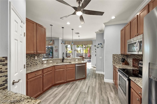 kitchen with kitchen peninsula, appliances with stainless steel finishes, ornamental molding, sink, and decorative light fixtures