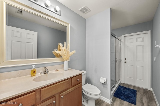 bathroom with hardwood / wood-style flooring, vanity, toilet, and walk in shower