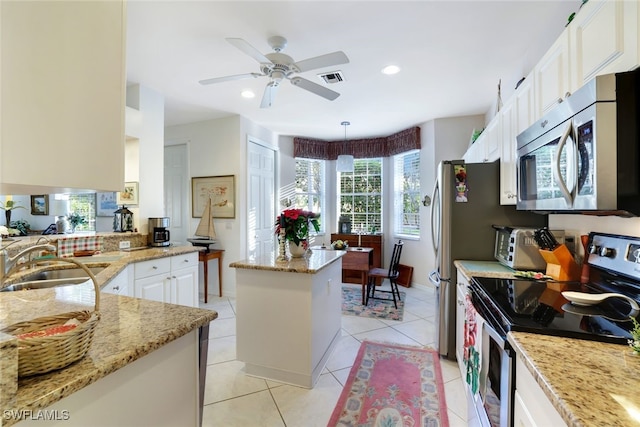 kitchen featuring white cabinets, sink, hanging light fixtures, light tile patterned flooring, and stainless steel appliances