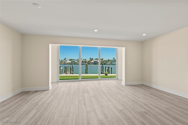 spare room with recessed lighting, baseboards, a water view, and light wood finished floors