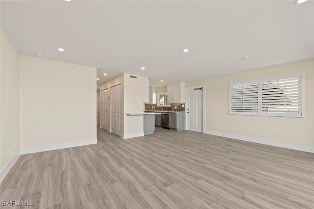 unfurnished living room featuring light wood finished floors, baseboards, and recessed lighting