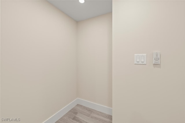 clothes washing area with light wood finished floors and baseboards