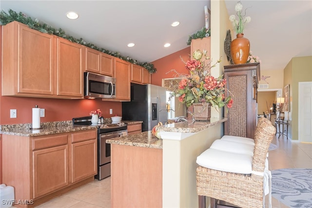 kitchen with light stone counters, stainless steel appliances, and light tile patterned flooring