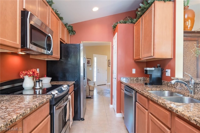 kitchen featuring light stone counters, vaulted ceiling, stainless steel appliances, light tile patterned flooring, and sink