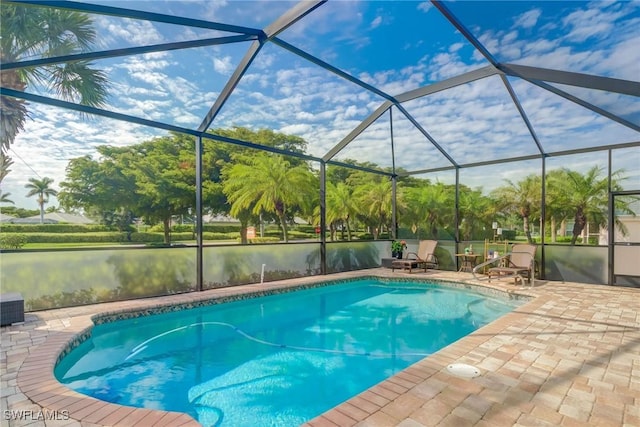 view of swimming pool featuring a patio, glass enclosure, and a water view