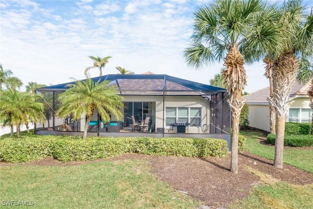 rear view of property featuring a lawn, a lanai, and a patio area