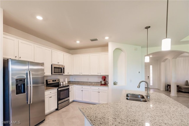 kitchen featuring light stone countertops, appliances with stainless steel finishes, sink, pendant lighting, and white cabinetry