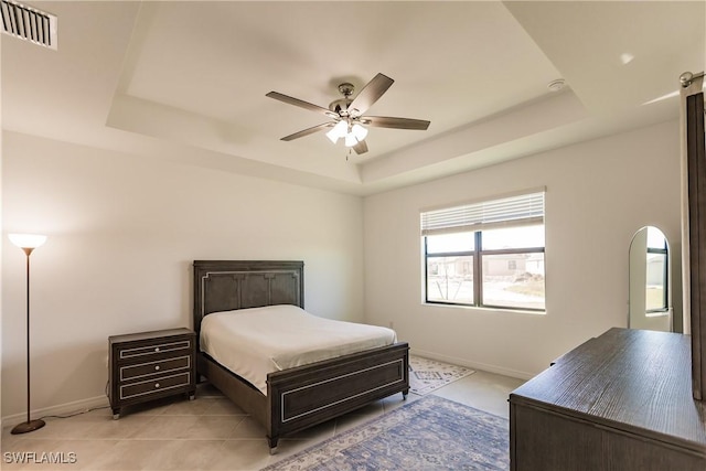 tiled bedroom featuring a tray ceiling and ceiling fan