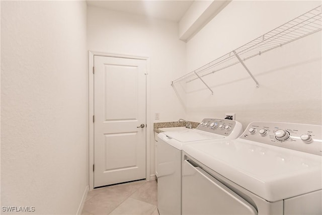 clothes washing area with light tile patterned flooring, sink, and washing machine and clothes dryer