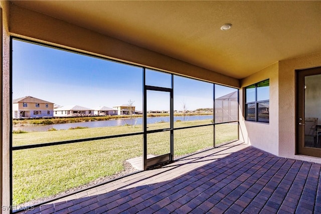 unfurnished sunroom featuring a water view