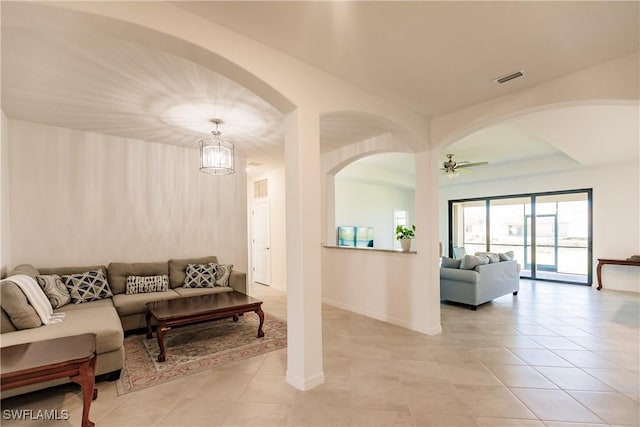 living room with light tile patterned floors and ceiling fan with notable chandelier