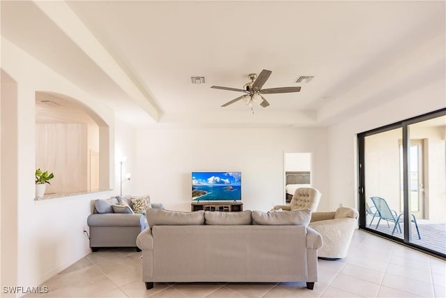 tiled living room with a tray ceiling and ceiling fan