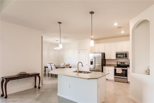 kitchen with light stone countertops, appliances with stainless steel finishes, sink, pendant lighting, and white cabinets