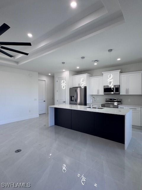 kitchen with stainless steel appliances, sink, white cabinets, a kitchen island, and hanging light fixtures