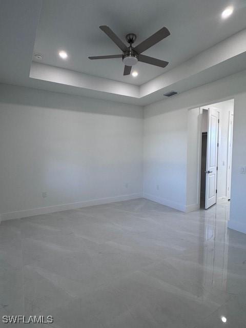 unfurnished room featuring ceiling fan and a tray ceiling