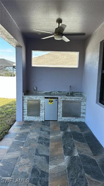 view of patio with ceiling fan, sink, and an outdoor kitchen