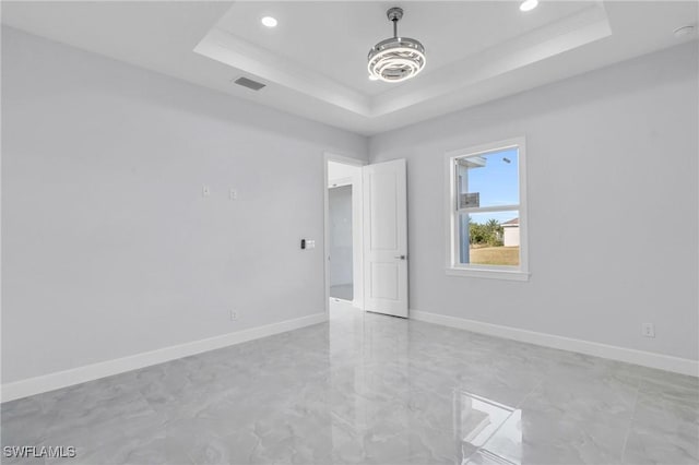 empty room with a raised ceiling and crown molding